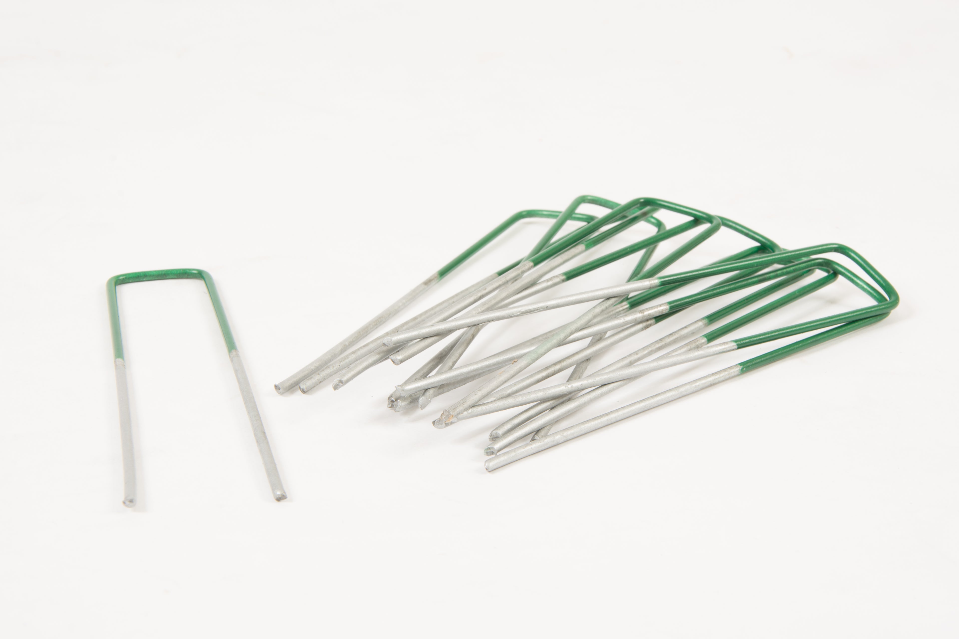 Set of metal needles with green handles on a white background
